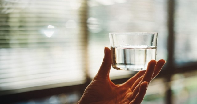 A hand holding a glass of water